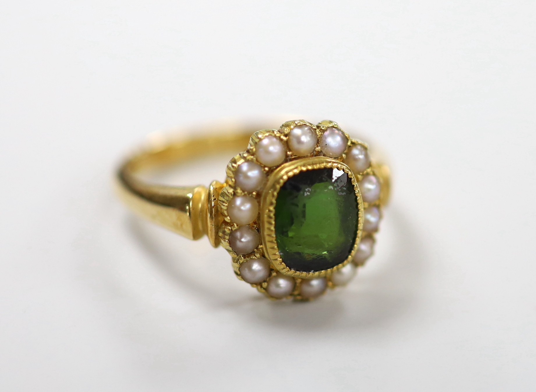 An Edwardian 18ct gold, green tourmaline and split pearl set oval cluster ring, size S, gross weight 6 grams.